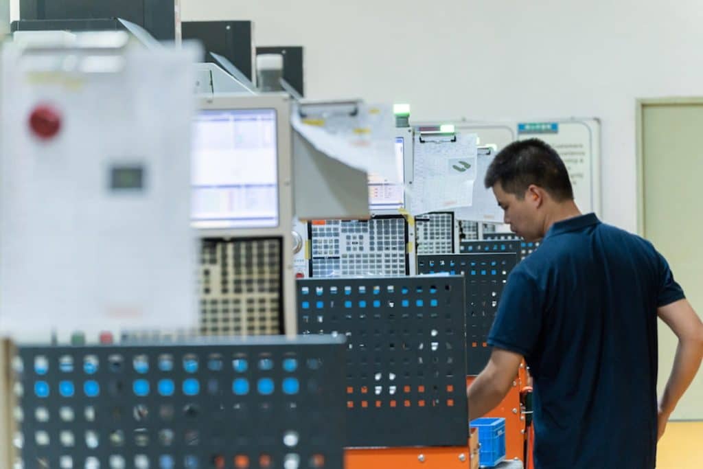 Worker operating precision metal fabrication equipment in an industrial facility