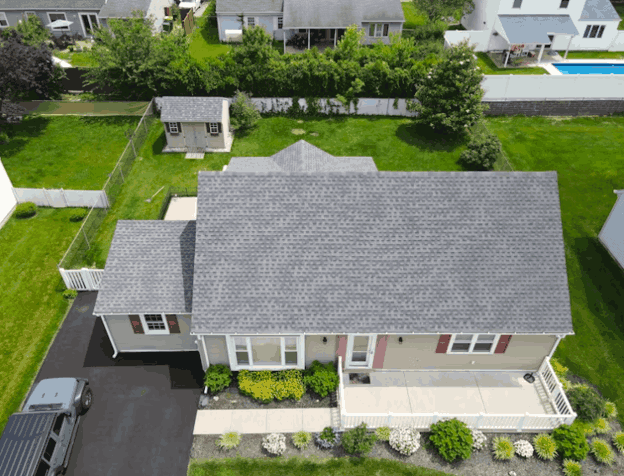Aerial view of a single-story suburban home with a gray shingle roof and landscaped yard
